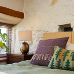 beautiful bed by a window with stone wall