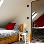 single bed by door to the bathroom with bath