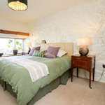 double bed with large window and white stone wall