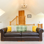 large dark brown leather sofa with cushions and throws