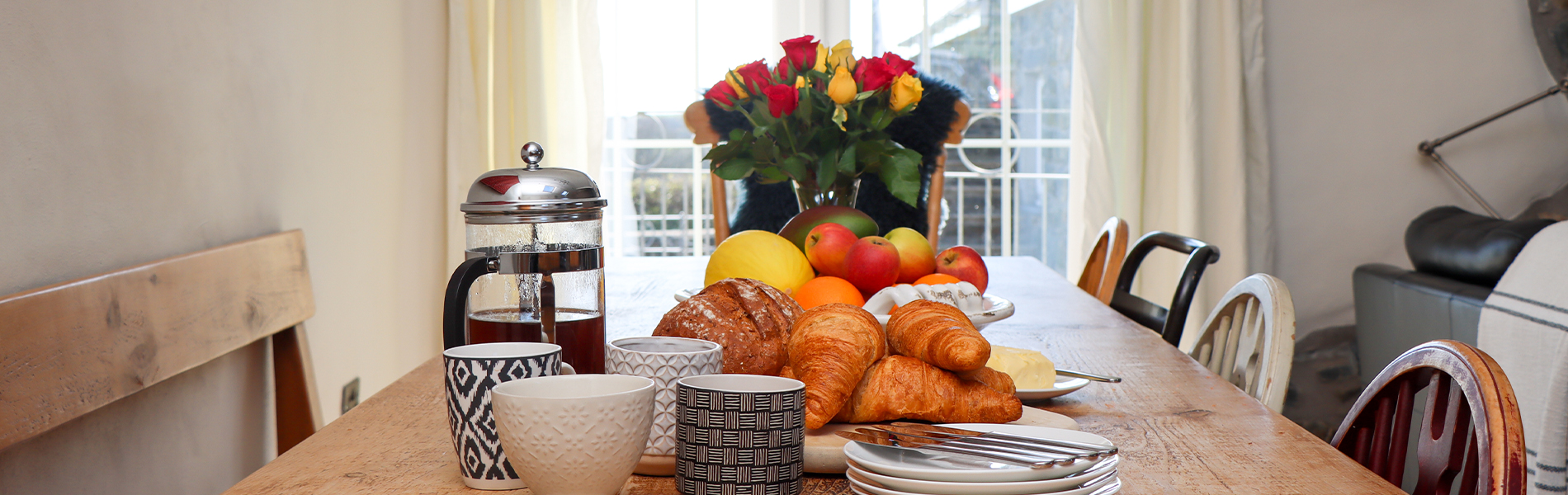 bwrdd gyda bwyd a blodau yn y canol