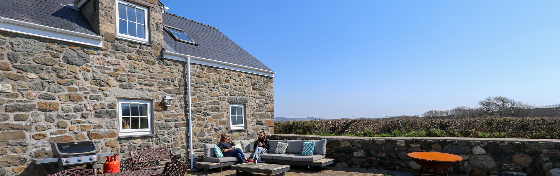 2 person yn eistedd tu allan yn yr haul