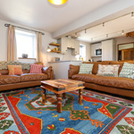 ystafell fyw gyda carped lliwgar a chegin tu nol